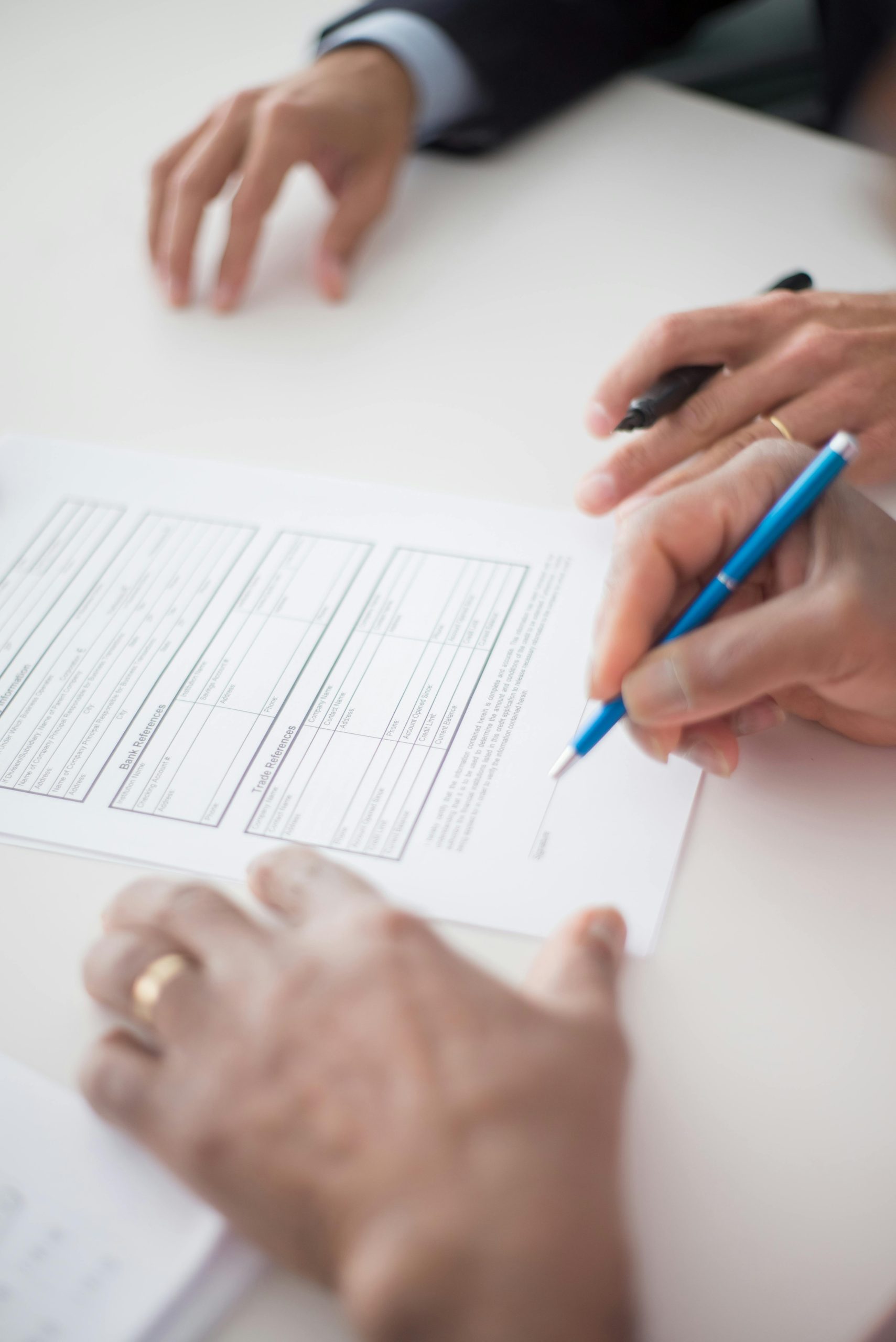 Close-up of hands signing a business document on a white surface with a pen.